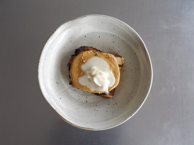 Peanut butter and labneh on toast in a speckled bowl